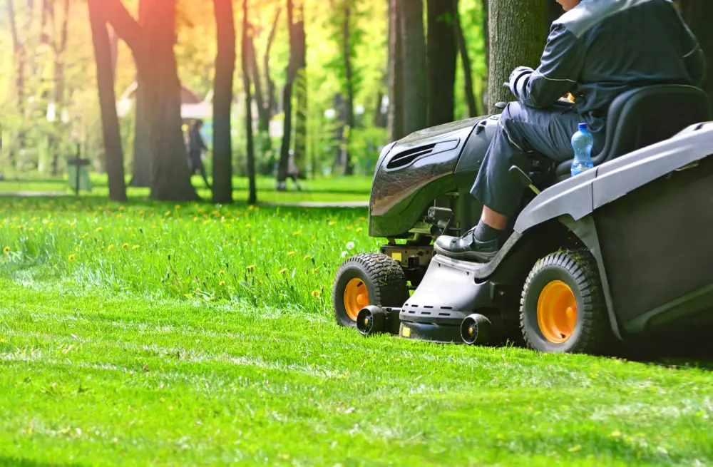 A man cutting his lawn with a riding lawn mower.