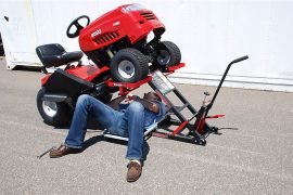 A man working on the underside of a riding lawn mower.