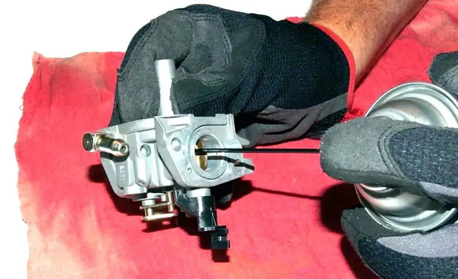 Closeup of a carburetor being cleaned.