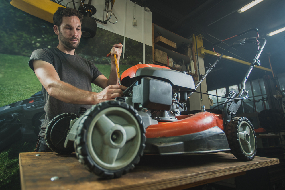 A man preparing to fix a lawn mower on his work table.