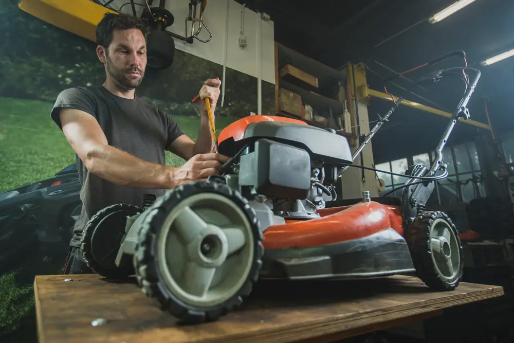 A man preparing to fix a lawn mower on his work table.