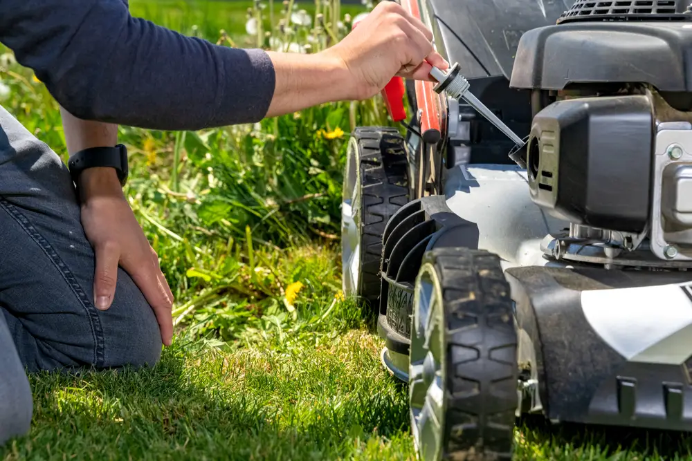 Person checking the oil level in their lawn mower.