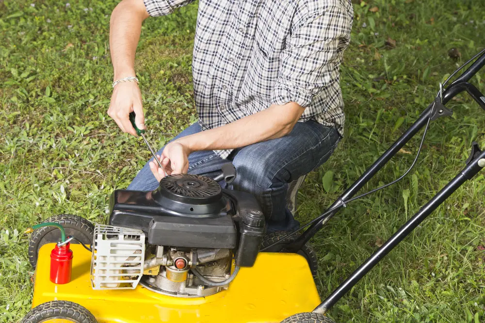 Man doing some maintenance on a lawn mower.