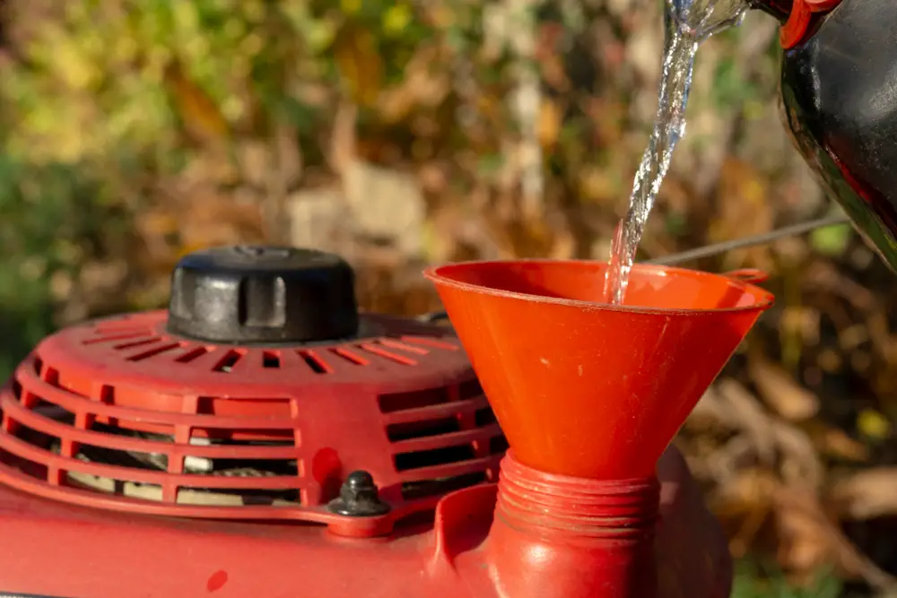 A closeup of a lawn mower being filled with oil.