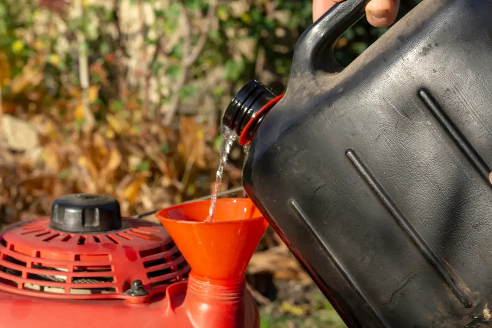 Closeup of fresh oil being poured into a lawn mower.