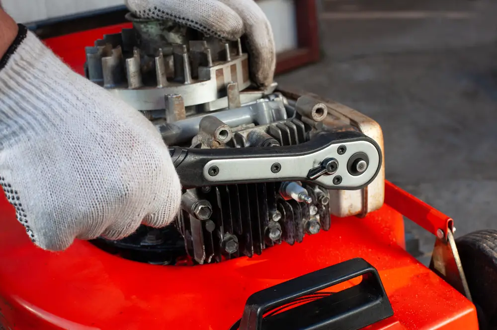 Closeup of a person working on a lawn mower engine.