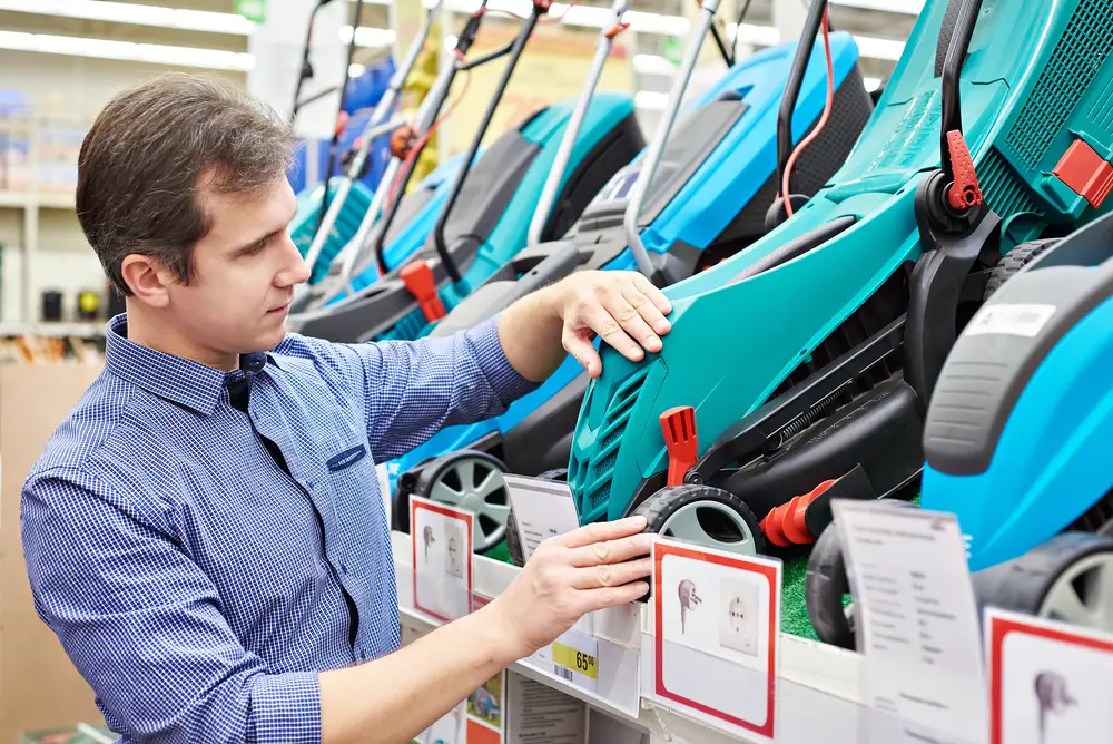 A man looking at some lawn mower options in the store.