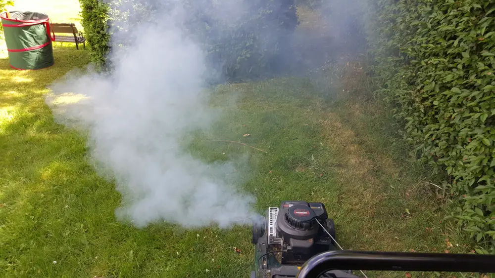 Lawn mower smoking in a yard.