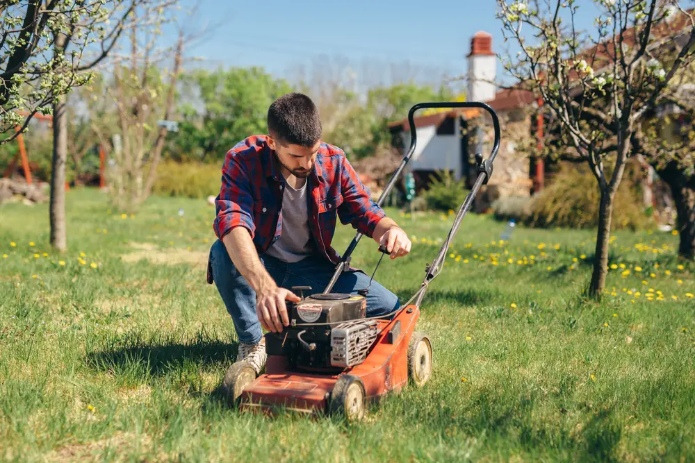 Man taking a look at his lawn mower.