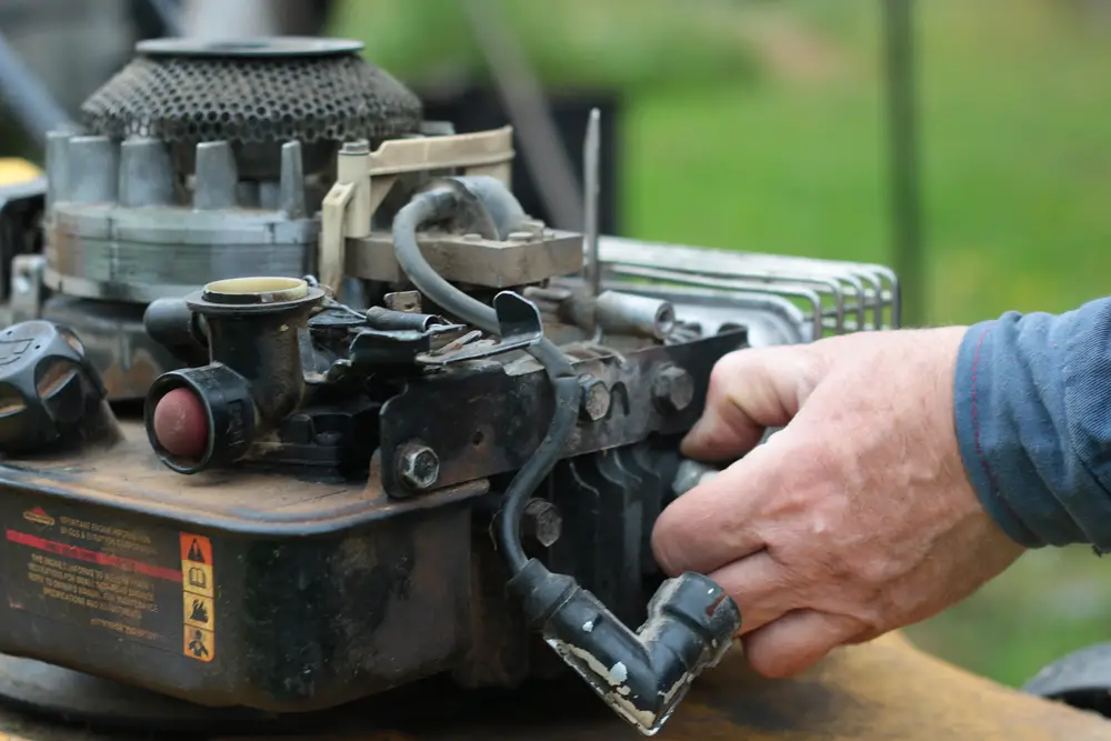 A man performing maintenance on his lawn mower.