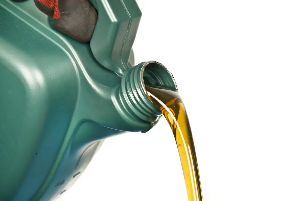 A closeup of oil pouring from a green container.