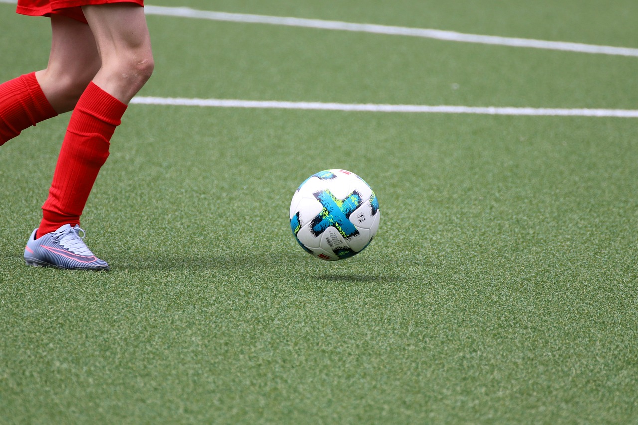 A soccer player about to kick a soccer ball on an artificial grass field.