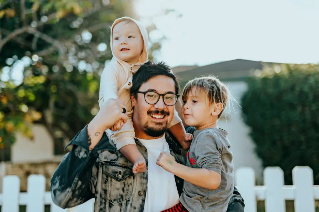 A father with his two kids on their lawn.