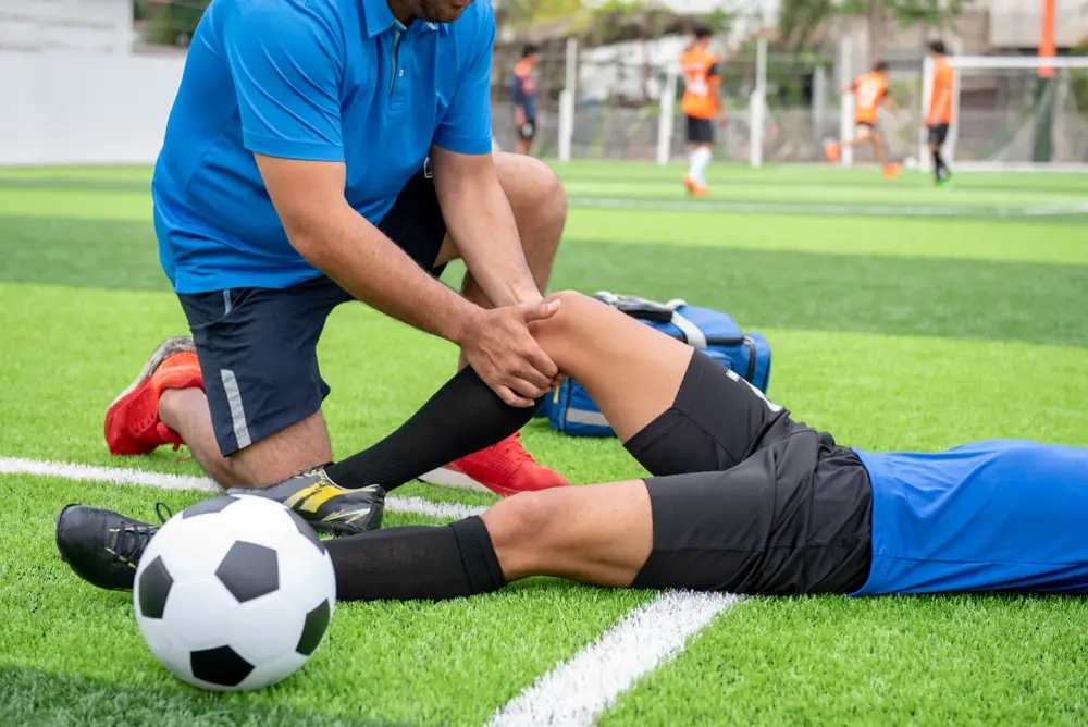 A soccer player getting checked for an injury on a field.