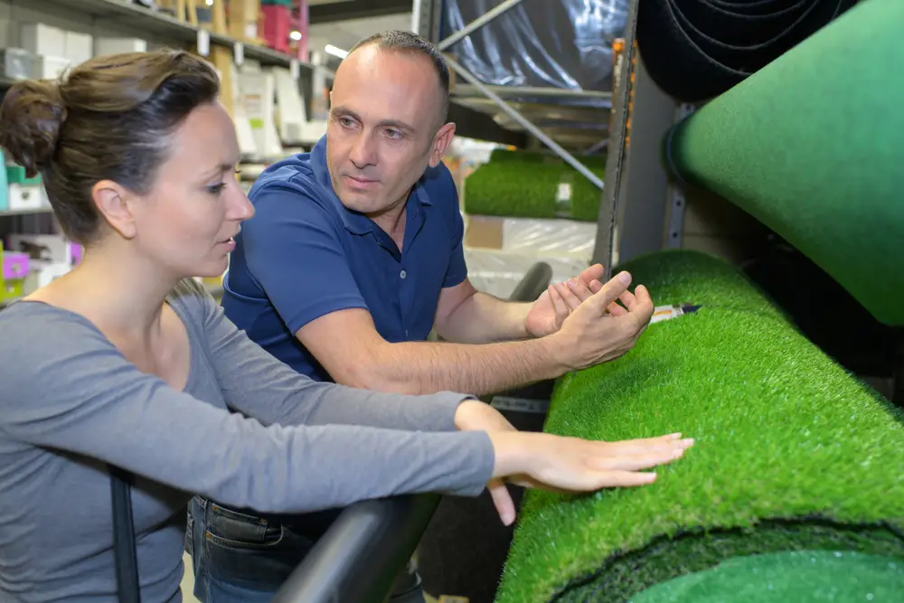 A man and woman talking about artificial grass in a store.