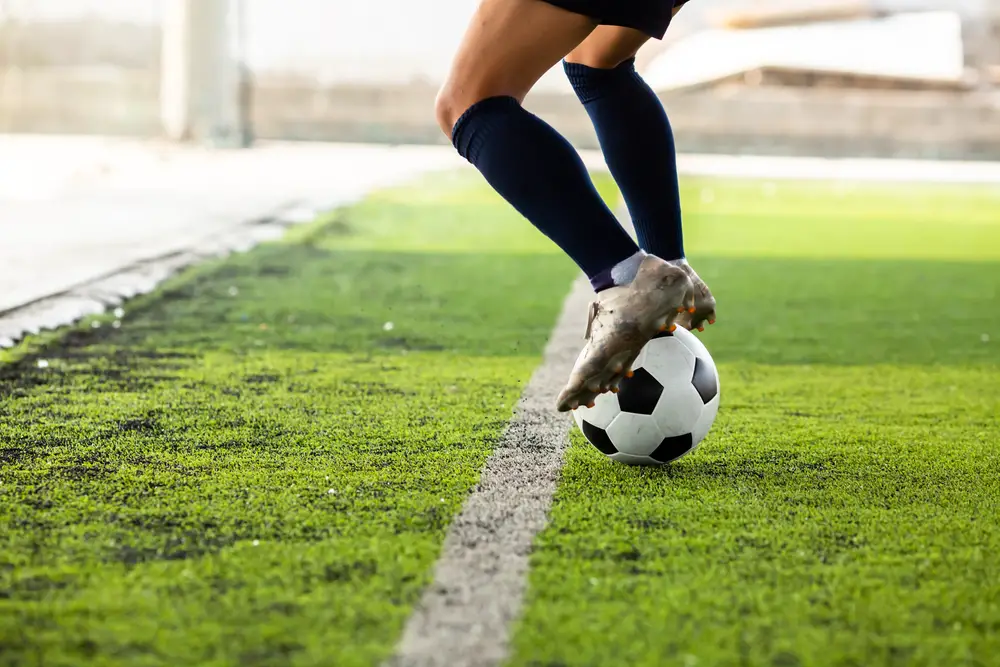 A soccer player practicing on an artificial grass field.