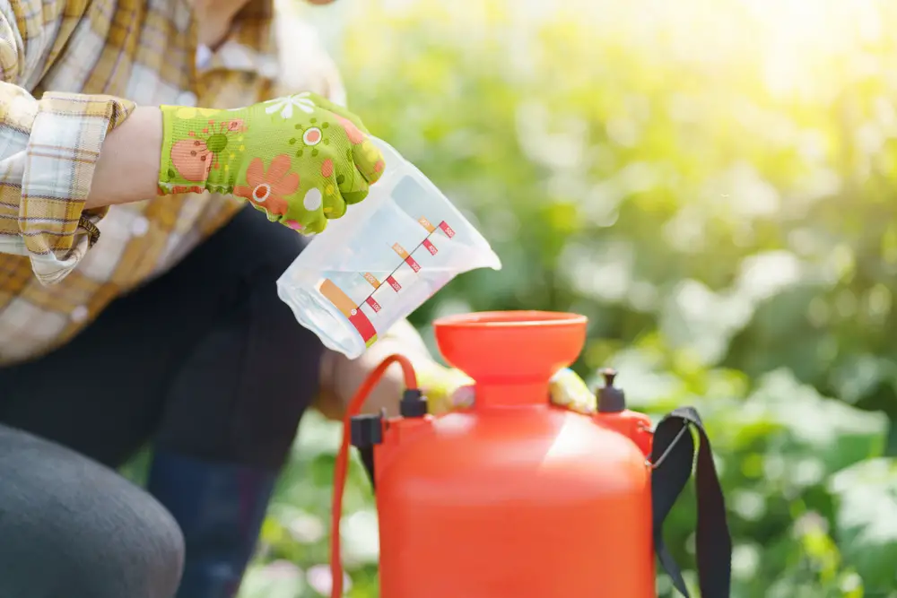 Woman pouring a liquid into a fertilizer distributor.