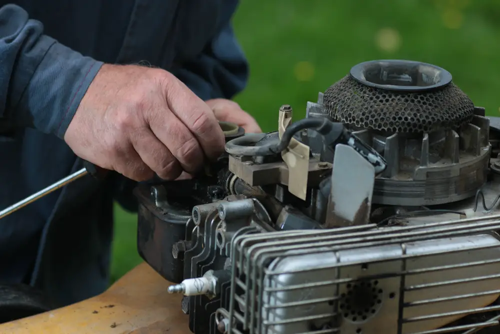 A closeup of a man working on his lawn mower.