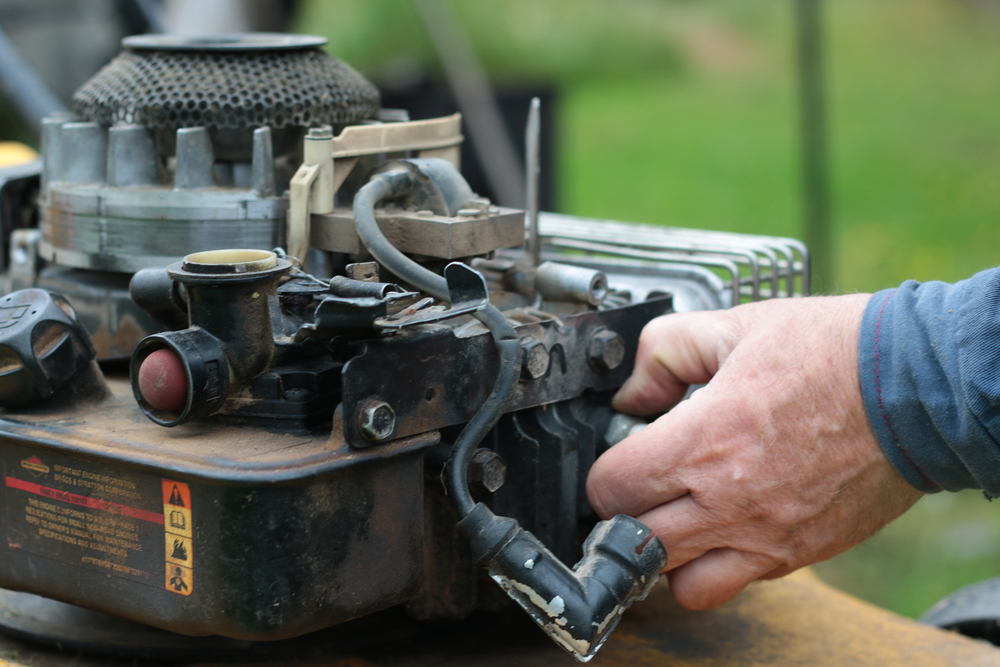 Closeup of someone working on a lawn mower.
