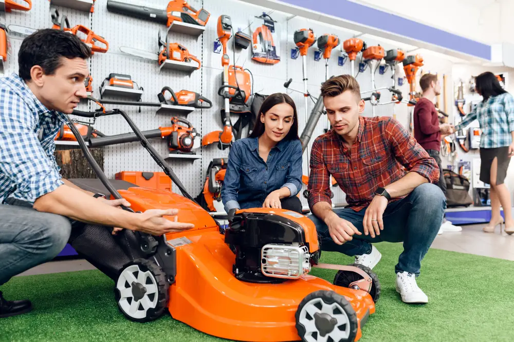 A couple talking to a sales representative in a lawn and garden store about a lawn mower.