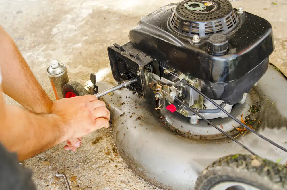 A man working on his gray lawn mower.