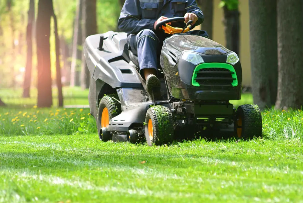 A man cutting his lawn with a riding lawn mower.