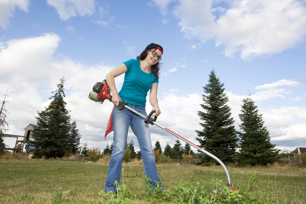 A woman using a weed whacker.