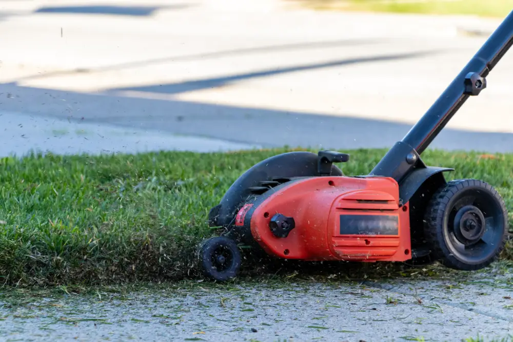 An edger trimming the edge of a patch of grass.