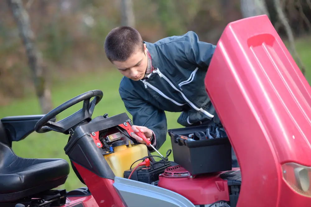 A man testing a riding lawn mower battery.