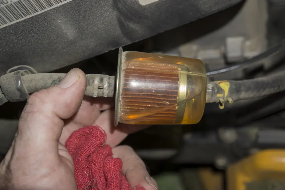 A closeup of a mechanic checking a fuel filter.