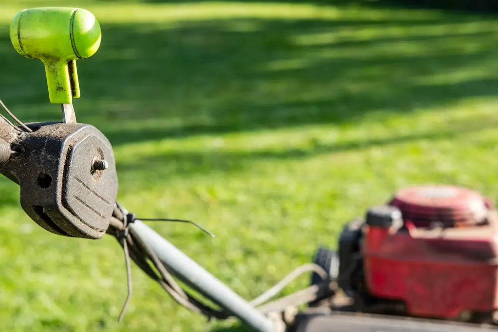 A closeup of a green throttle lever on a lawn mower.